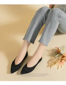 Detail view of black knit pointed-toe flat shoes worn by a model in a casual setting