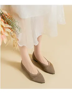 Detail of beige knitted pointed toe flat shoes worn with a light summer skirt.