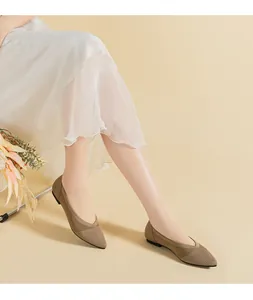 Elegantly styled model wearing pointed-toe knitted flat shoes in khaki with a white skirt