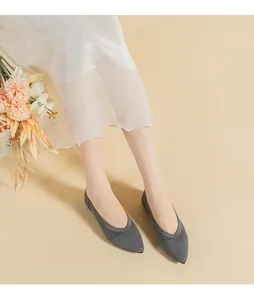 Elegant grey pointed-toe knitted flat shoes worn with a white sheer skirt on beige