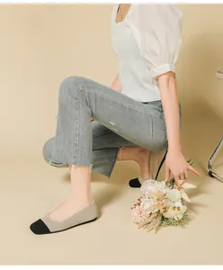 Detailed view of beige knit flat shoes with black square toe cap on model