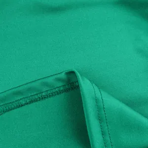 Primo piano dettagliato delle cuciture fini e della trama di un abito da sera verde vibrante.
