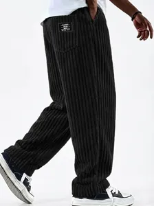 Detailed view of men's black wide-leg corduroy pants with vertical ribbed texture