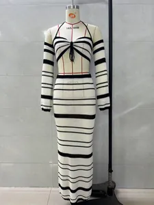 Elegant black and white striped two-piece knit set with halter top and maxi skirt.