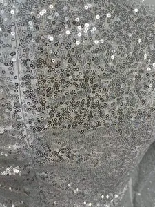 Détail en gros plan des paillettes argentées denses sur tissu de robe de soirée.