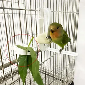 Vista dettagliata delle clip per cibo per uccelli che tengono foglie in una gabbia.