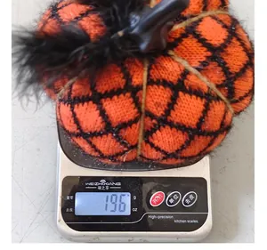 Detailed macro view of a handmade knitted orange and black pumpkin ornament weighing 196g.