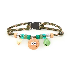 Macro view showing the cartoon biscuit, bell, and ice cream charms on a woven pet collar.