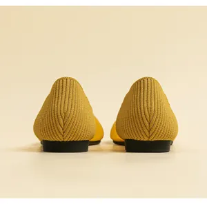 Rear view close-up of yellow knit pointed-toe flats showing textured heel detail