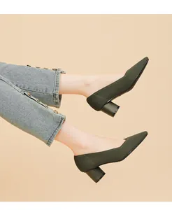 Close-up of olive green knit pointed toe pumps with chunky heels on model.