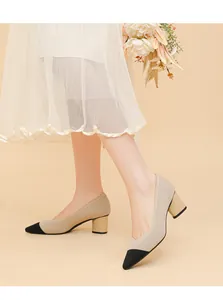 Close-up detail of beige ribbed chunky heel pumps with black cap toe and V-cut design
