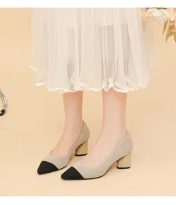 On-foot close-up of beige and black pointed-toe block heel pumps with ribbed texture