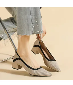 Close-up of beige knitted pointed-toe pumps with chunky mid-heels and black trim