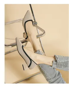 Detailed view of beige knit pointed toe pumps with black trim and chunky heels