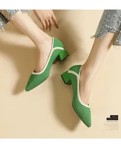 Side view of elegant green knitted pointed-toe pumps with chunky heels on model's feet