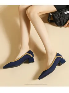 Close-up detail of navy blue knitted pointed-toe pumps featuring yellow trim and chunky heels.