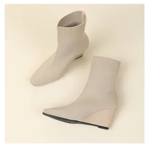 Nahaufnahme der Strickstruktur von beigen Sock Boots mit Keilabsatz und Karree