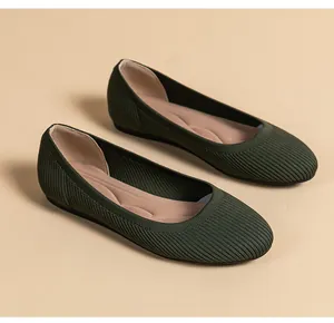 Gros plan de chaussures plates en tricot vert foncé à bout rond et texture côtelée.