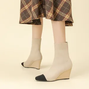 Elegante beige gestrickte Keilabsatz-Stiefeletten mit schwarzer Kappe und 8 cm Absatz.