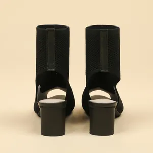 Rear view of black knit peep-toe ankle boots with cutout heel and chunky mid-heel.