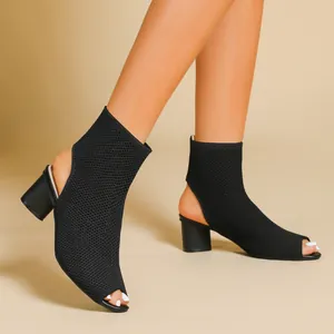 Close-up view of elegant black knitted peep-toe ankle boots with a stable chunky heel