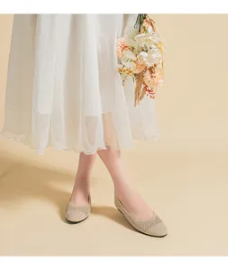 Dettaglio di ballerine in maglia traspirante abbinate a una gonna bianca a pieghe.