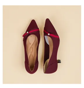 Macro detail view of elegant burgundy knit kitten heel pumps with pearl decorative strap.
