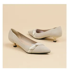 Detail view of beige pointed-toe flyknit kitten heels with elegant pearl bow.