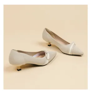 Detailed view of beige fly-knit pointed-toe kitten heels featuring an elegant pearl bow