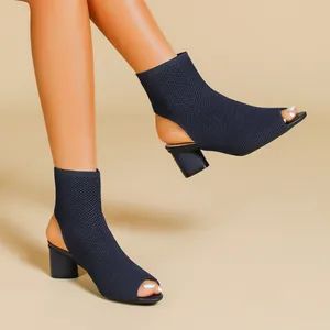 Detailed view of navy blue knit peep-toe booties with chunky heels on a model.