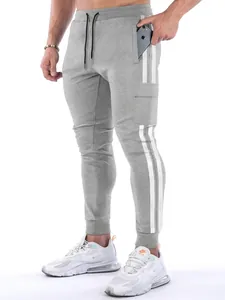 Close-up of grey men's sports joggers with white side stripes and multi-pocket detail