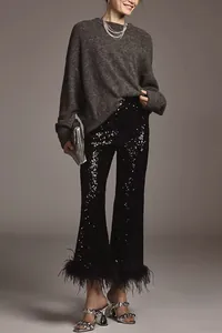 Close-up detail of black sequin flared pants featuring elegant feather trim on hem