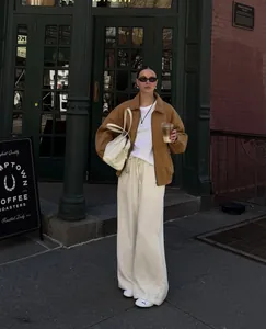Modische braune Wildlederjacke im Vintage-Stil für Damen vor einem Straßencafé