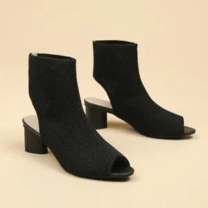 Close-up of black knitted peep-toe ankle boots with chunky heel and mesh texture