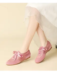 Close-up shot of pink satin ballet flats featuring ribbon laces and suede details