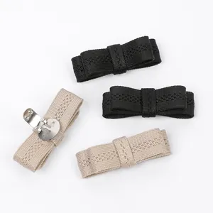 Detail view of knitted bow shoe clips with detachable metal buckle in black and beige