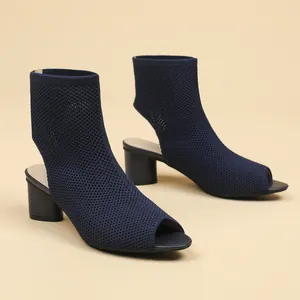 Close-up detail of navy blue knit peep-toe ankle boots with chunky heel and hollow back.