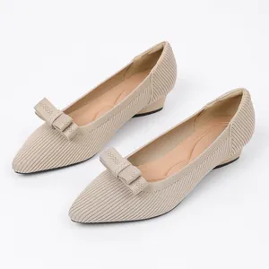 Detailed view of beige knitted pointed-toe flat shoes with a matching knit bow.