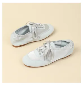 Detailed view of light blue satin ballet flats with ribbon laces and suede trim.