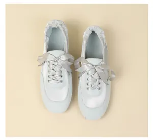 Top down view of light blue satin and suede ballet style sneakers with elegant ribbon laces