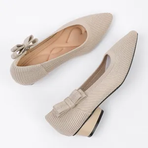 Close-up of elegant beige knitted pointed-toe heels featuring a decorative bow shoe accessory