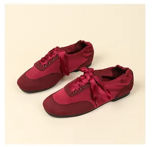 Detail view of burgundy satin ballet flats featuring elegant ribbon lacing and soft suede toe.