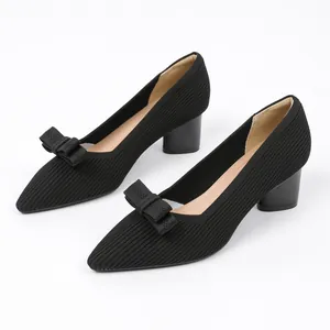 Detailed view of detachable black knitted bow decoration on elegant pointed-toe pumps