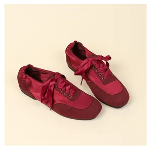 Detailed close-up of dark red satin and suede ballet flats with elegant ribbon laces