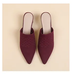 Close-up detail of burgundy knitted pointed-toe mules featuring textured wave pattern