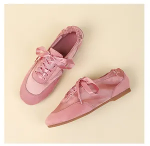 Detailed view of elegant pink satin and suede ballet flats featuring ribbon laces