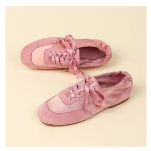 Detail view of pink satin ballet flats with ribbon ties and soft suede texture