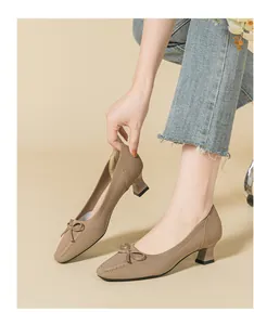 Macro view of elegant tan knitted square toe chunky heel pumps with a chic bow detail