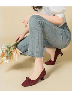 Detailed view of burgundy knitted square-toe pumps with delicate bow tie accent
