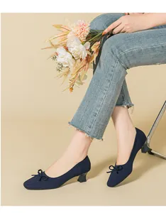 Navy blue knit pumps with square toe, bow detail, and chunky heels shown on model.